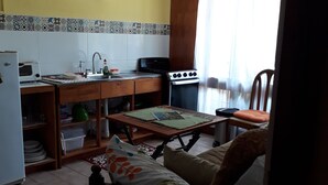 Eine kleine Küche mit Mikrowelle, Herd, Spüle und Deckenventilator.