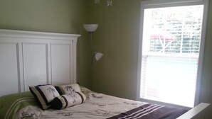 A bedroom with a bed, a ceiling fan, a window, and a nightstand.