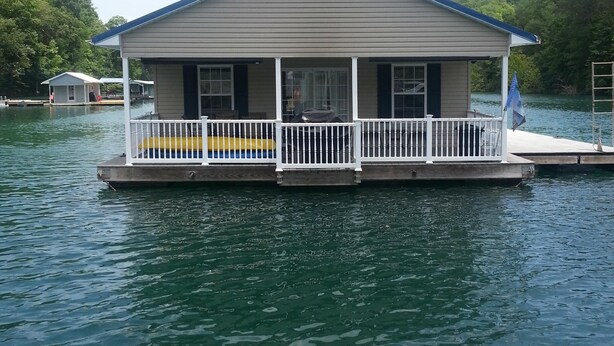 A houseboat with a covered deck and a small porch.