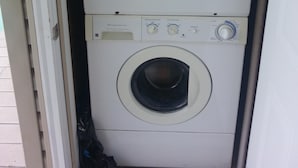 A compact, white laundry room with a front-loading washer and dryer stacked vertically.