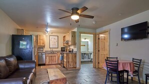 A compact living space with a kitchenette, a dining area with a table and chairs, a leather sofa, and a ceiling fan. - Mt. Joseph Lodge in Downtown Joseph: Unit #3 (Joseph)