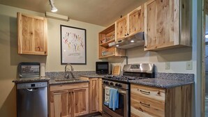 A kitchen with wooden cabinets, a stainless steel stove, a dishwasher, and a microwave. - Mt. Joseph Lodge in Downtown Joseph: Unit #3 (Joseph)