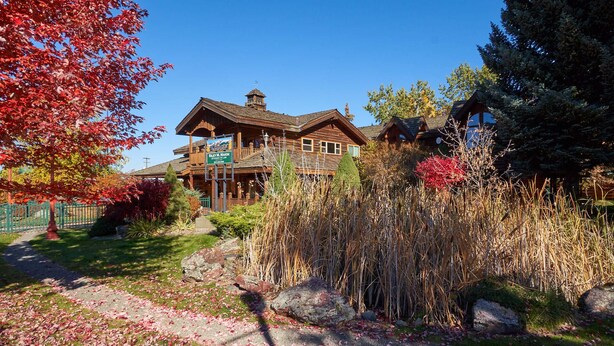 A lodge with a prominent wooden structure, a visible signboard, and a well-maintained garden with rocks and foliage. - Mt. Joseph Lodge in Downtown Joseph: Unit #3 (Joseph)