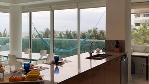 Una cocina moderna con una isla grande, un lavamanos y vistas a palmeras y una hamaca.