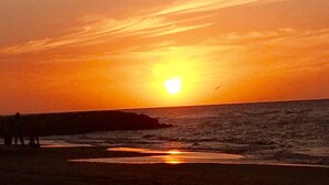 Um pôr do sol sobre o oceano com uma costa rochosa.
