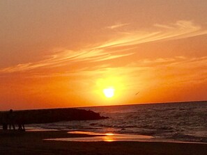Tramonto sull'oceano con una costa rocciosa.