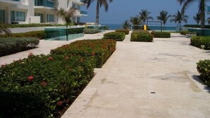 Un hotel moderno con zona de piscina, palmeras y vistas al océano.