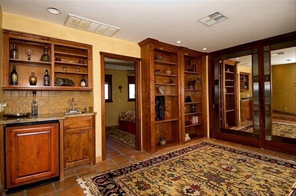 A spacious room with a large wooden cabinet, a patterned rug, and a mirrored wall.