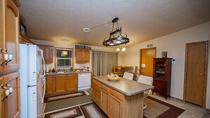 A kitchen with wooden cabinets, a white refrigerator, a central island, and a hanging light fixture.
