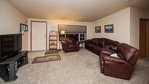 A living room with a television, leather sofas, a coffee table, and a fireplace.