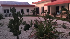 A modern building with a red roof, white walls, and a gravel courtyard with cacti and other plants. - VIDA Chelem- MAR vacation property (Chelem)