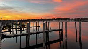 Une jetée bordant le rivage, avec des piliers en bois et une surface d’eau calme qui reflète le ciel.