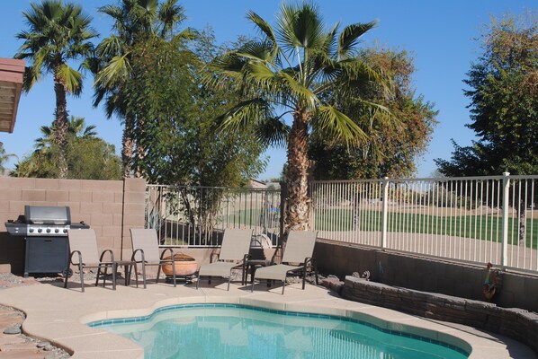 A backyard with a swimming pool, lounge chairs, a grill, and palm trees. - 3BR Home with Heated Private Pool, Golf, & Mountain Views (Avondale)