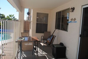 A covered patio with a pool, a table with chairs, a guitar, and a small cabinet. - 3BR Home with Heated Private Pool, Golf, & Mountain Views (Avondale)