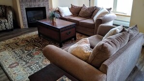 Un salon avec une cheminée, un canapé, une table basse et un tapis à motifs.