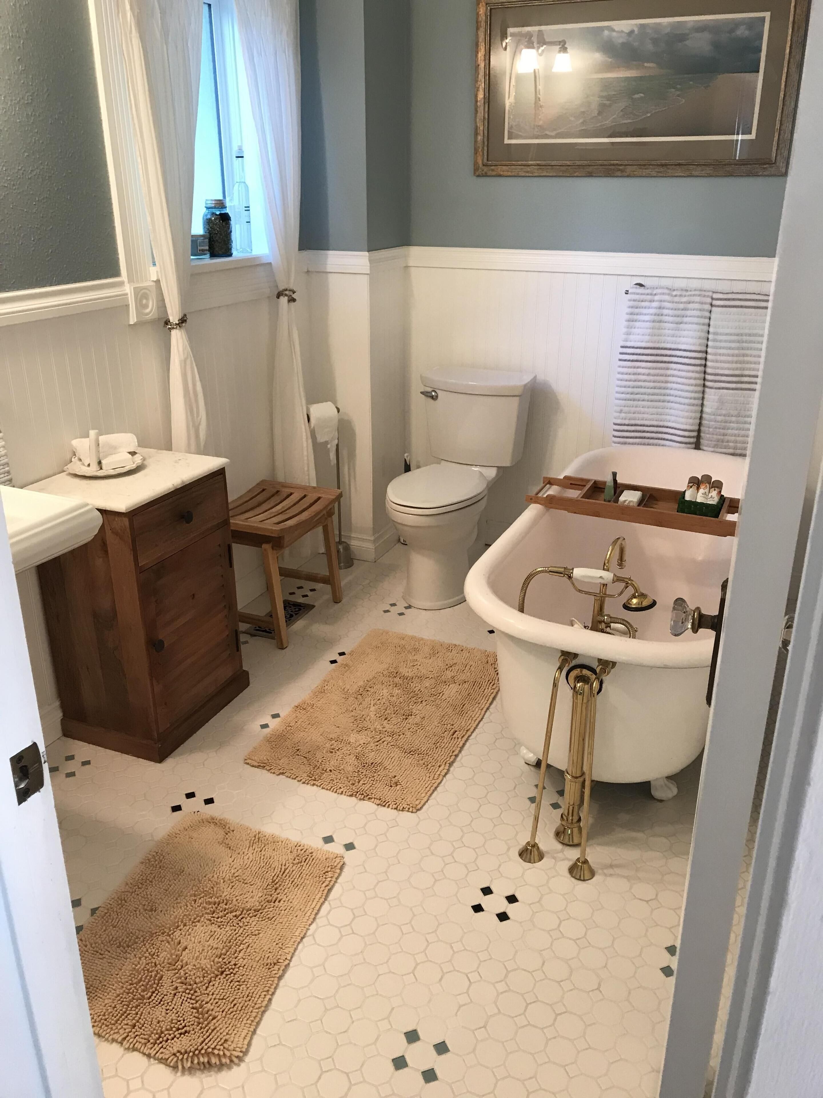 A bathroom with a toilet, sink, and vintage-style bathtub.