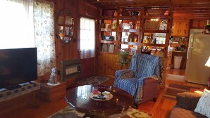 Una sala de estar acogedora con detalles de madera, un televisor, un sofá y una mesa de centro con un control remoto.