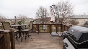 A wooden deck with outdoor furniture, a grill, and a view of houses in the background. - Outstanding home, spacious, close to everything (Omaha)