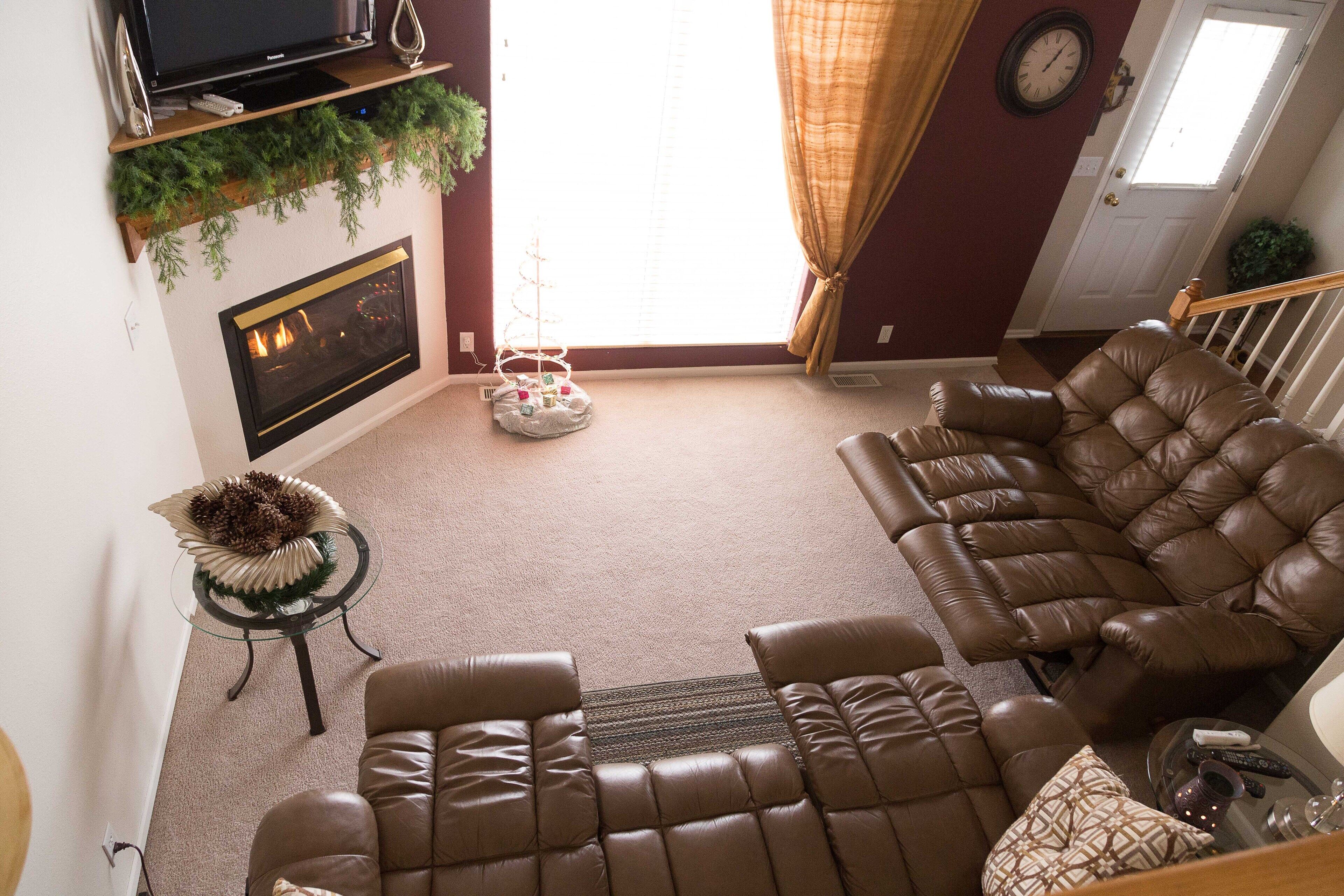 Ein Wohnzimmer mit Kamin, Ledersofas, Fernseher und Weihnachtsbaum.
