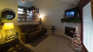A living room with a leather sofa, a glass coffee table, a fireplace, and a television mounted on the wall. - Outstanding home, spacious, close to everything (Omaha)