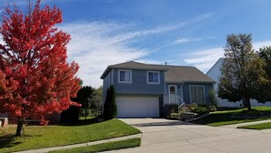 A two-story residential house with a garage, surrounded by well-maintained lawns and trees with autumn foliage. - Outstanding home, spacious, close to everything (Omaha)
