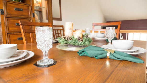 A dining table set with white plates, bowls, and glassware, surrounded by wooden chairs. - Outstanding home, spacious, close to everything (Omaha)