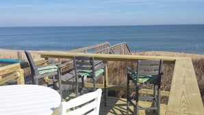 A wooden deck with a table and chairs overlooking a beach and the ocean. - OCEANFRONT☆One level living w/ramp access to house & dune deck. Walk to dining!  (Kitty Hawk)