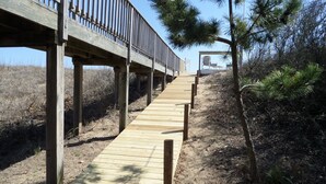 A wooden boardwalk leading to a beach area with a wooden fence overhead. - OCEANFRONT☆One level living w/ramp access to house & dune deck. Walk to dining!  (Kitty Hawk)