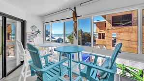 A room with a view of construction, a ceiling fan, and a table with chairs.