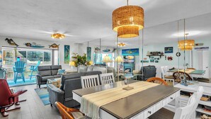 A spacious living area with a dining table, chairs, and a large window overlooking a patio.