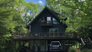 A two-story cabin with a balcony, a covered porch, and a car parked in front. - lake George Adirondack Chalet  (Lake George)