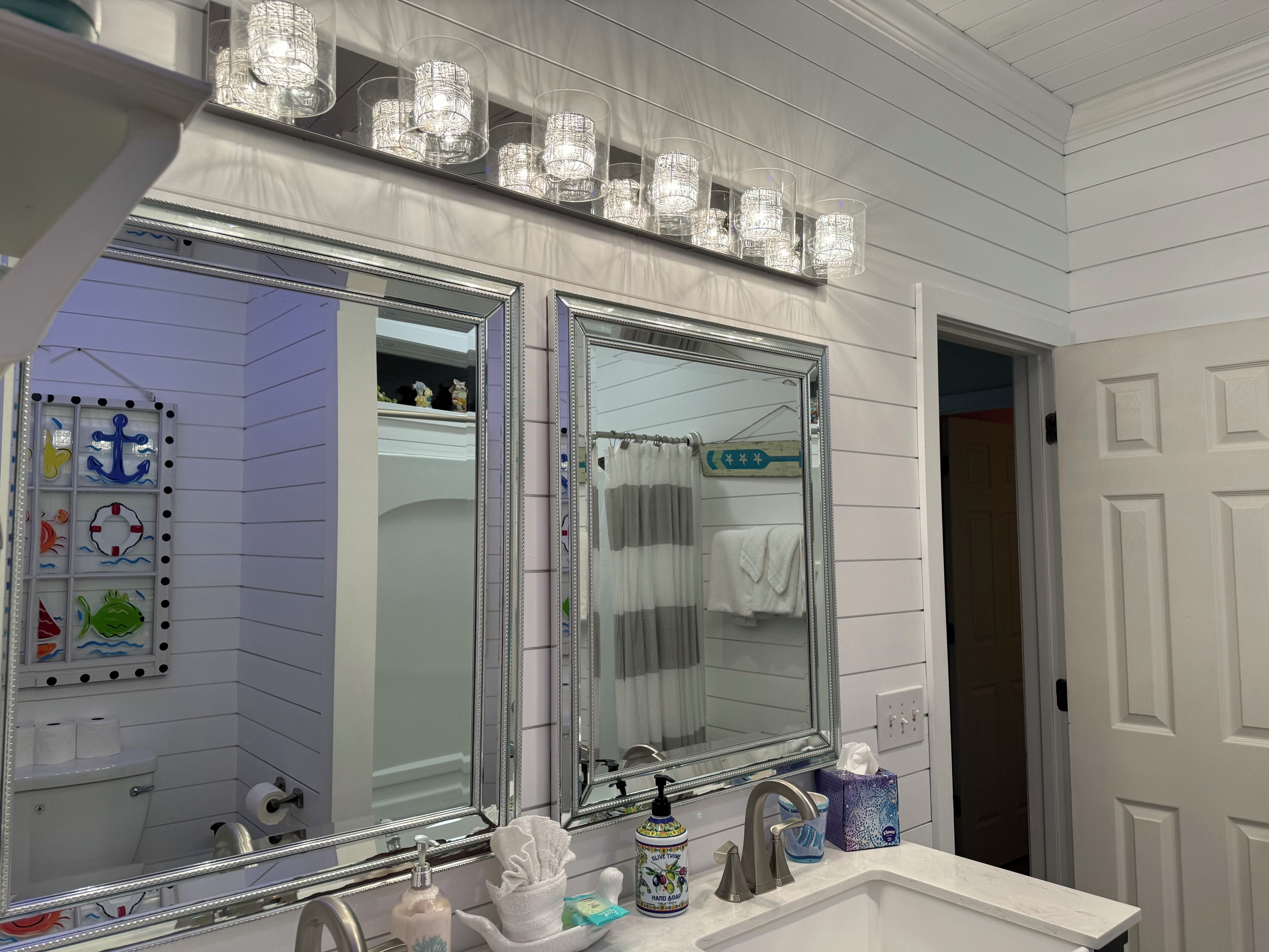 A bathroom with two large mirrors, a vanity with a sink, and a shower area.