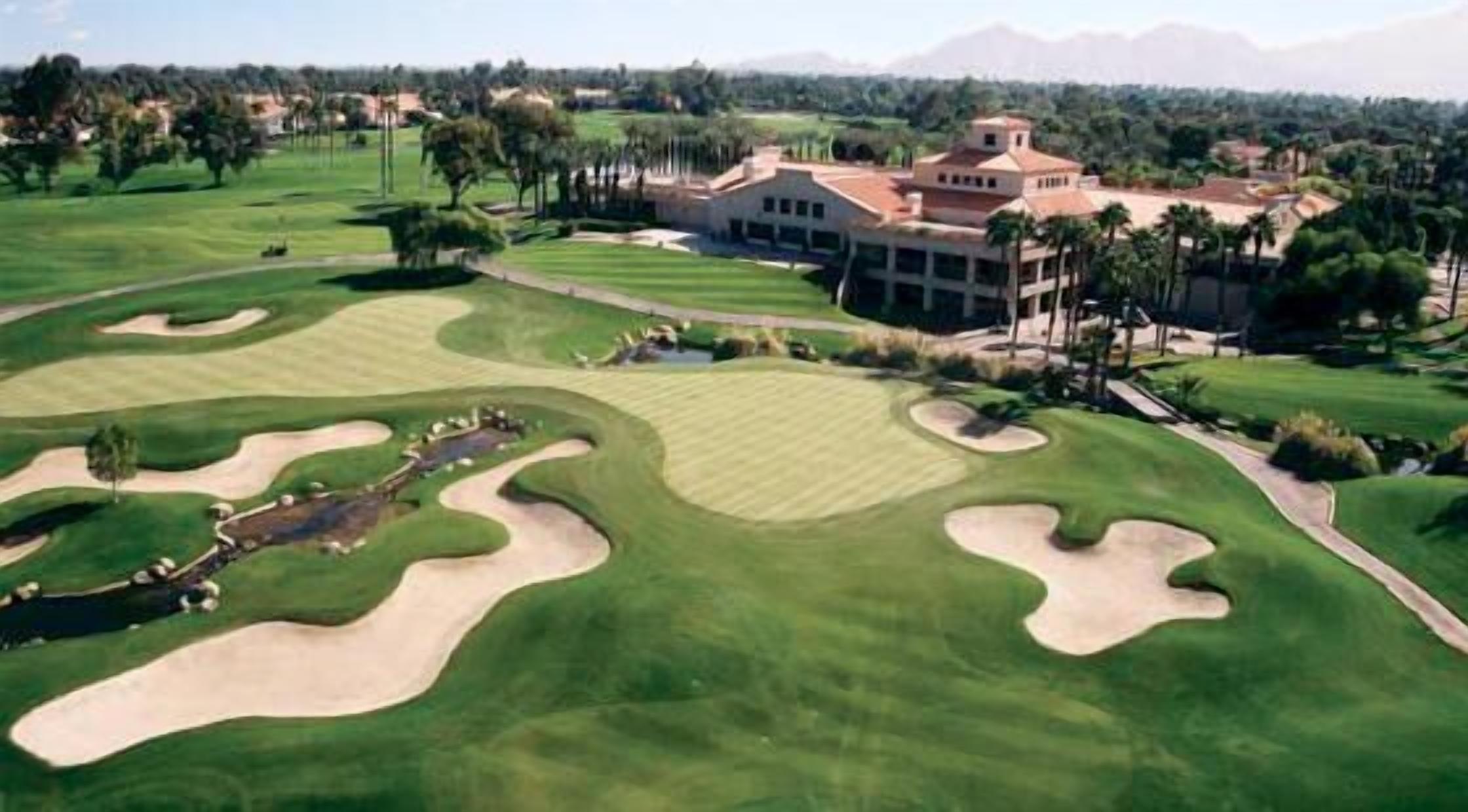 A golf course with bunkers and a clubhouse.