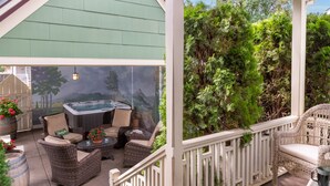 Un patio couvert aménagé avec des meubles en osier, un jacuzzi et une vue sur une végétation luxuriante.