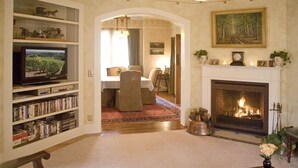 Un salon avec une cheminée, un téléviseur et une bibliothèque.