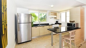 A modern kitchen with a stainless steel refrigerator, a microwave, and a stove. There is a window providing natural light and a view of greenery outside. - Playa Turquesa, Beachfront, Ocean view, pool, 2 Bd. Luxury Condo, Wifi, Smart TV (Bavaro)
