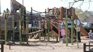 Uma área de recreação infantil com diversas estruturas para escalar e um escorrega.