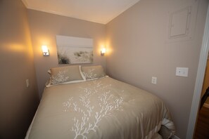 A bedroom with a bed, two wall-mounted lights, and a framed picture on the wall. - 👓200 steps to beach. CLEAN, quiet residential get away! Near Barefoot Landing! (North Myrtle Beach)