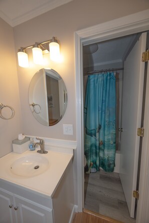 A bathroom with a sink, mirror, and three light fixtures. - 👓200 steps to beach. CLEAN, quiet residential get away! Near Barefoot Landing! (North Myrtle Beach)