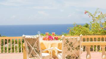 Un balcon avec une table dressée pour deux personnes, offrant une vue imprenable sur l’océan.