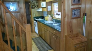 A wooden interior with a kitchen area including a sink, stove, and cabinets.