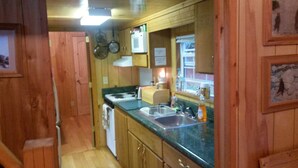 A compact kitchen with wooden cabinets, a microwave, a sink, and a stove.