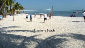 Partido de voleibol de playa en la playa Smathers, con jugadores y espectadores.