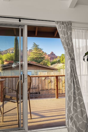 A balcony with a view of a mountainous landscape, a wooden fence, and a chair.