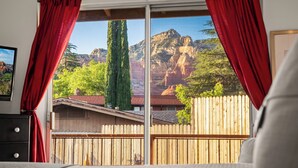 Une chambre avec une grande fenêtre, une clôture en bois et une vue sur la montagne.