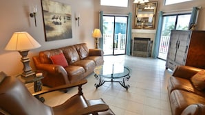A spacious living room with a leather sofa, a glass coffee table, and a fireplace. - beautiful Home 98 steps from the beach just off Thomas drive (Panama City)