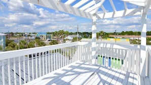 A white wooden deck with a view of a town and buildings in the background. - beautiful Home 98 steps from the beach just off Thomas drive (Panama City)