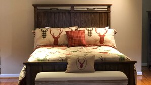 Une chambre à coucher avec une tête de lit en bois, un ventilateur de plafond décoratif et une couvre-lit à motifs, ornée de motifs de cerfs.