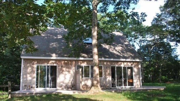 A single-story house with a brick exterior, large glass doors, and a tree in front. - Vineyard Haven, Quiet Setting Just Minutes from Ferry and Bus (Vineyard Haven)