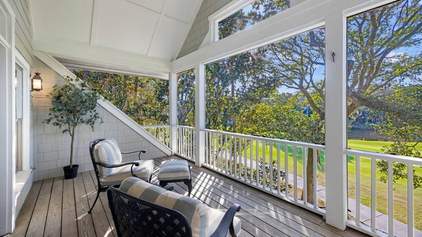 A covered porch with wooden flooring, white railings, and a view of a green landscape. - AMAZING Golf Views of Turtle Point 18th Hole! Pool Access! (Kiawah Island)